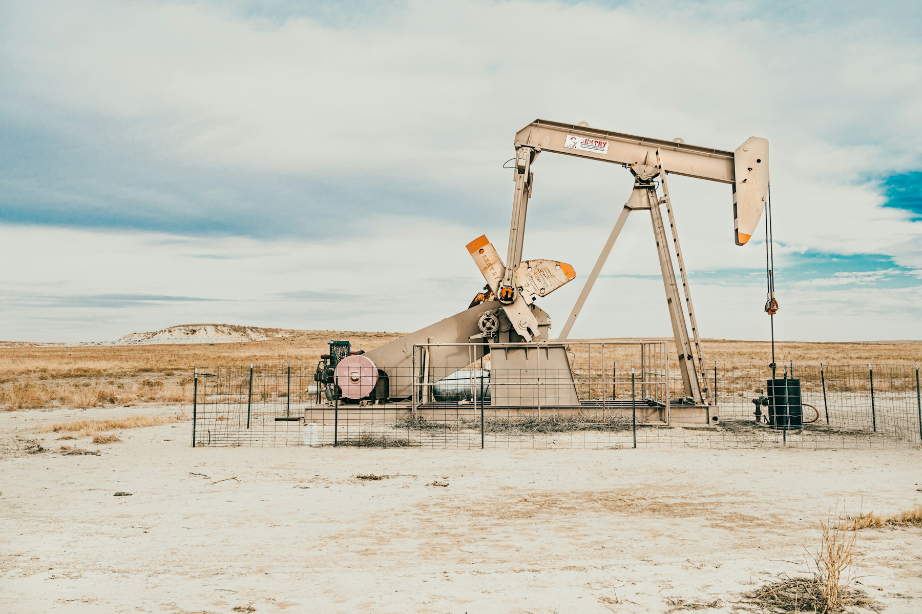 Oil pumpjack and wellhead equipment in an open oilfield